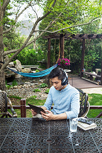 青年男人坐在院子里看平板电脑图片