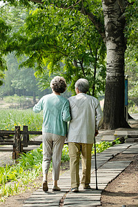 搀扶背影老年夫妇在公园里散步背景
