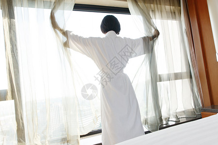 年轻女人在酒店房间里拉开窗帘高清图片