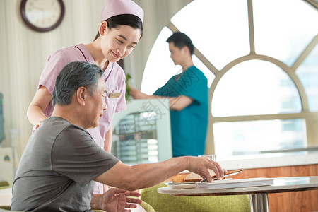 米色面包服护士照顾老年人用餐背景