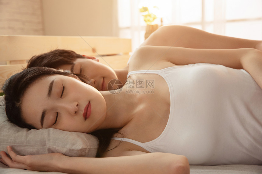 年轻夫妇躺在床上睡觉图片