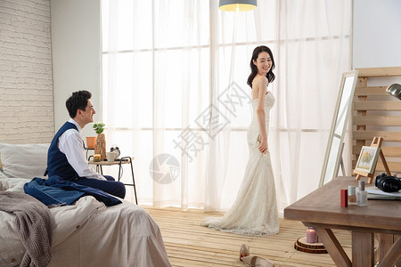 卧室里新婚的丈夫欣赏妻子穿婚纱的样子图片