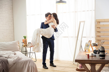 卧室里幸福的丈夫把妻子抱起来高清图片