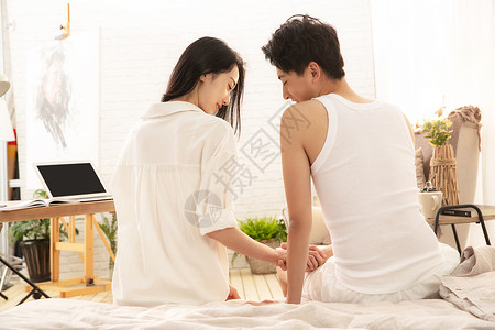 幸福的情侣坐在床上交流的背影图片