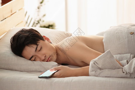 玩手机玩到睡着的年轻男人图片