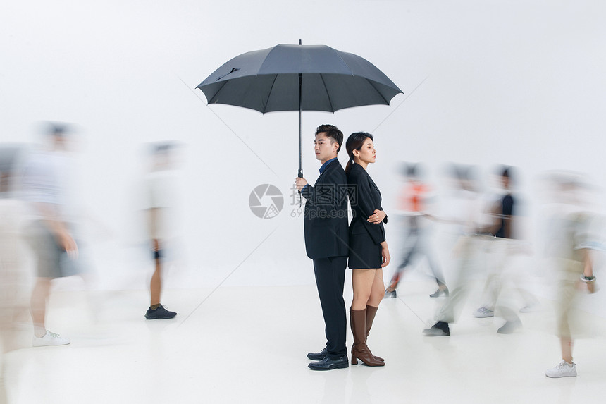 拿着雨伞的商务男女站在人群中图片