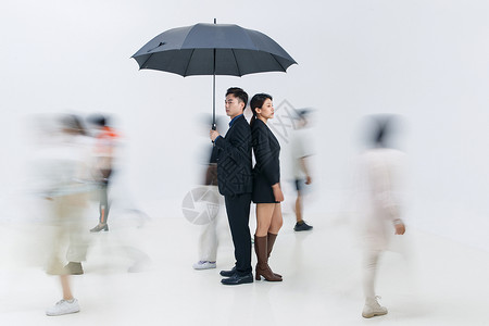 拿着雨伞的商务男女站在人群中高清图片