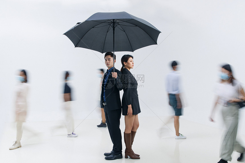 拿着雨伞的商务男女站在人群中图片