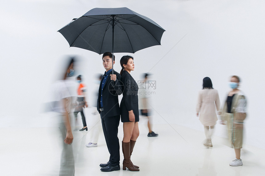 拿着雨伞的商务男女站在人群中图片