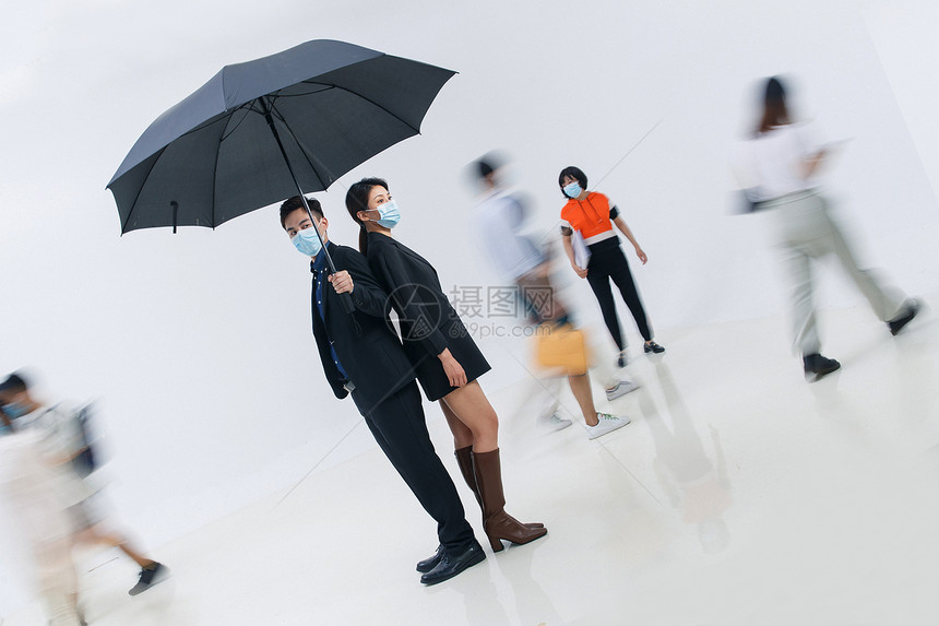 拿着雨伞的商务男女戴着口罩站在人群中图片