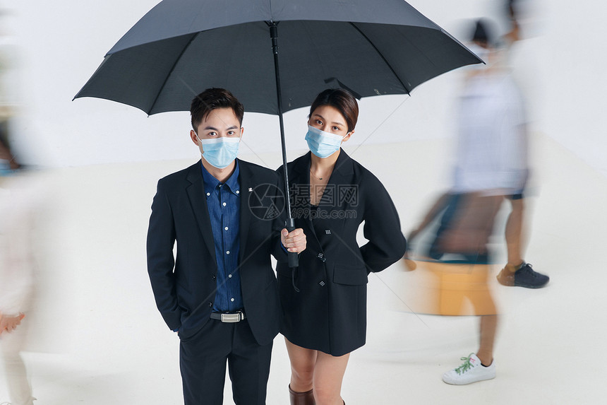 拿着雨伞的商务男女戴着口罩站在人群中图片