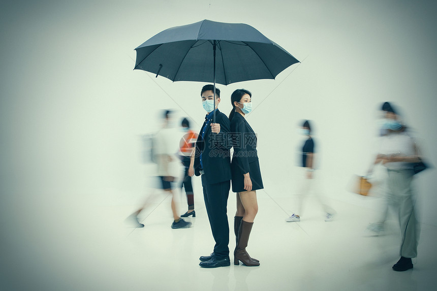 拿着雨伞的商务男女戴着口罩站在人群中图片