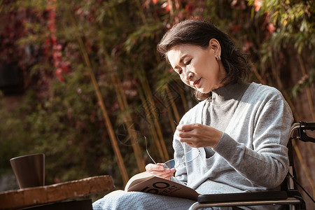 休闲看书晒太阳孤独的老年女人在院子里晒太阳背景