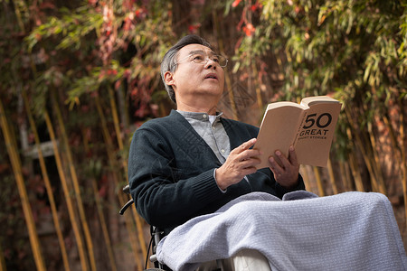 户外老年男人坐在轮椅上看书高清图片