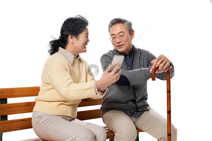 老年夫妇坐在长椅上看手机图片