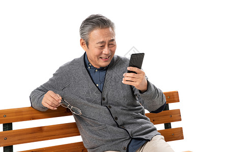 快乐老人坐在长椅上看手机高清图片