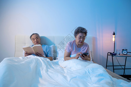 老年夫妇坐在床上看书看手机图片