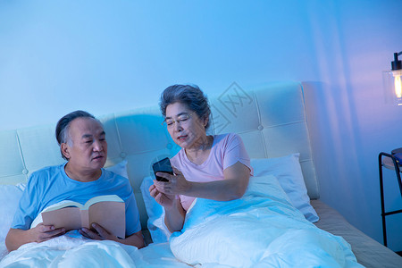 老年夫妇坐在床上看手机图片