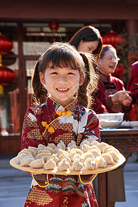 包饺子活动可爱的小女孩端着饺子背景