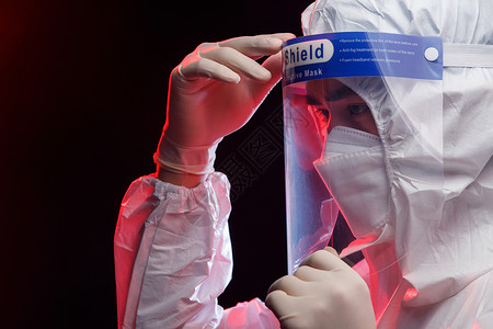 医药标签调整防护面罩的青年男医生背景