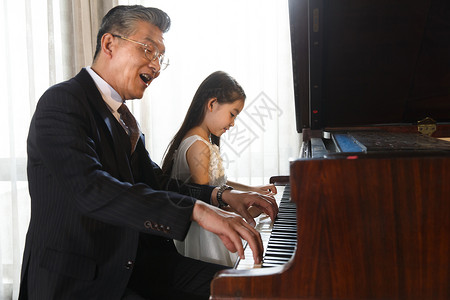 祖父和孙女一起弹钢琴高清图片