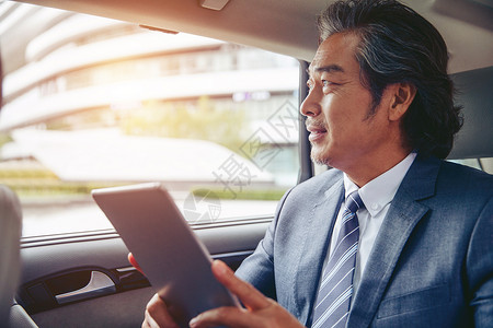 互联网外的商务男士坐在汽车里看平板电脑背景