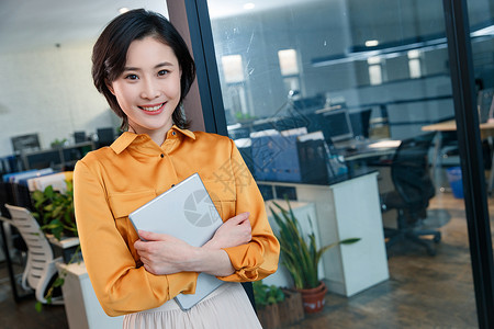 站着的女士在办公室里拿着平板电脑的商务女士背景