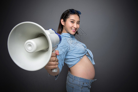 影棚怀孕的穿着时尚的孕妇拿着扩音器背景