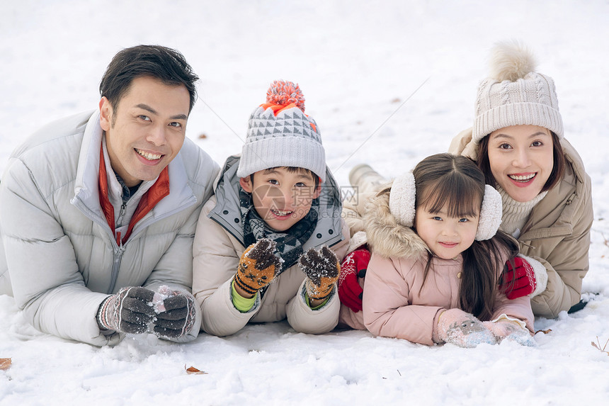 趴在雪地里玩耍的快乐家庭图片