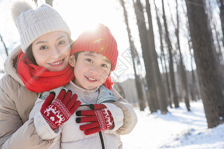 年轻妈妈带着孩子在雪地玩耍图片