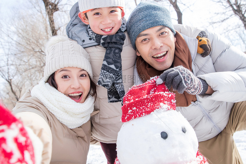 一家三口在雪地里堆雪人图片