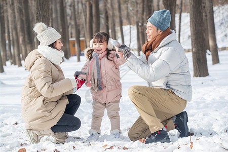 一家三口在雪地里玩耍图片