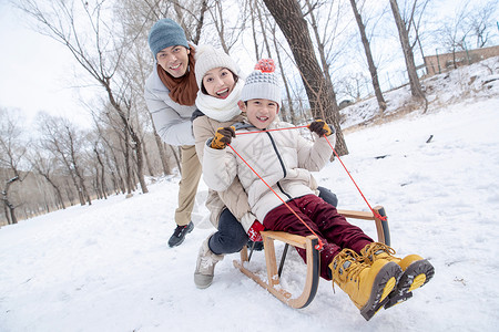 妈妈孩子玩雪在雪地上玩雪橇的一家人背景
