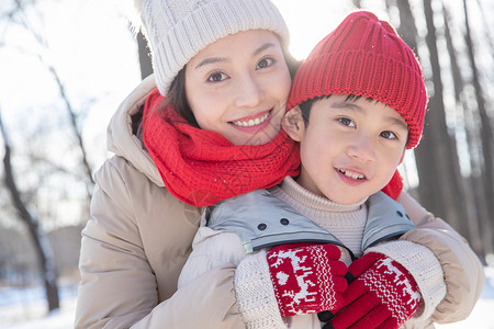 年轻妈妈带着孩子在雪地玩耍图片