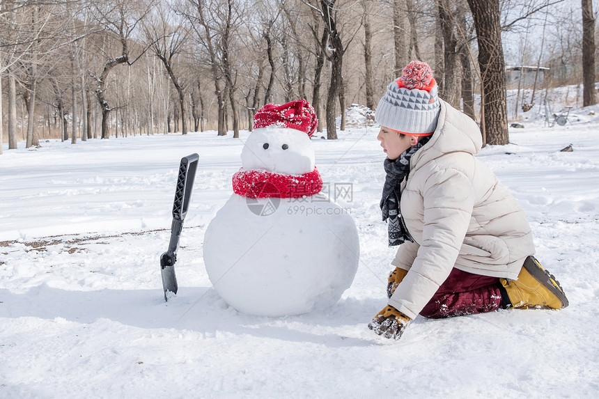 快乐的小男孩在雪地里堆雪人图片