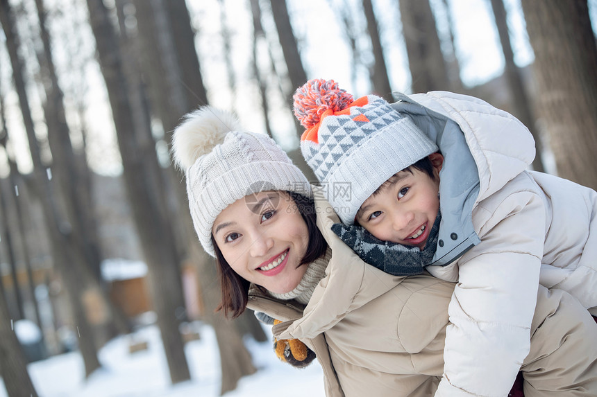 年轻妈妈带着孩子在雪地玩耍图片