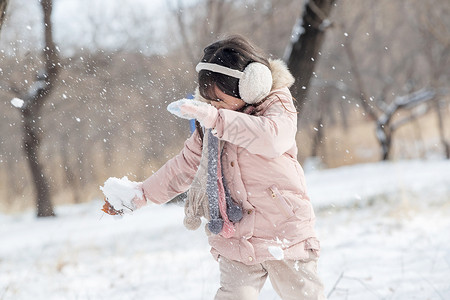 拿着雪球的人快乐的小女孩在雪地里玩耍背景