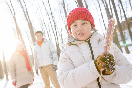 雪地上小男孩拿着糖葫芦高清图片