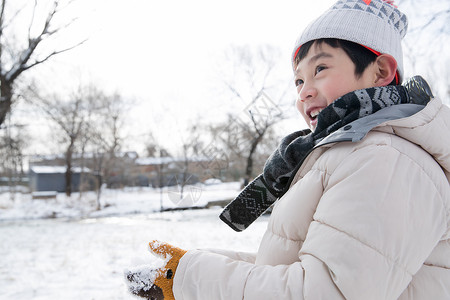 拿着雪球的人快乐的小男孩在雪地里玩耍背景