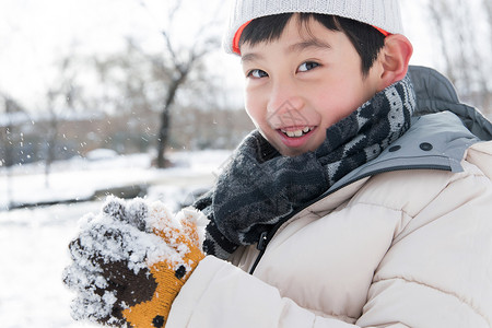 拿着雪球的人在外面玩雪的小男孩背景