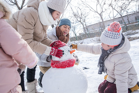 冬天堆雪人的女孩欢乐家庭在雪地里堆雪人背景