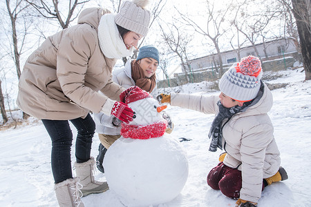 一家三口在雪地里堆雪人高清图片