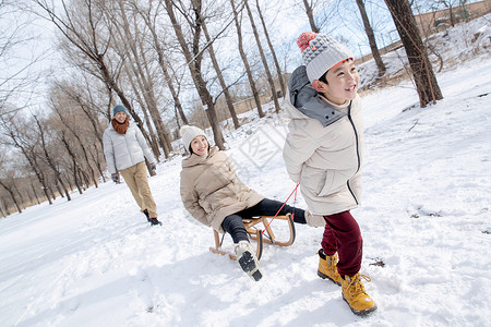 在雪地上玩雪橇的一家人高清图片
