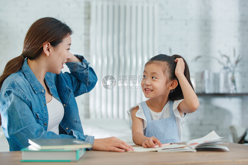 辅导女儿做作业的青年女人图片