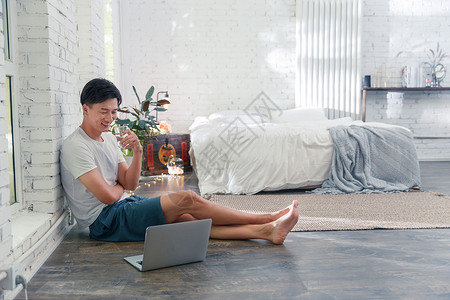 青年男人坐在地板上使用笔记本电脑高清图片