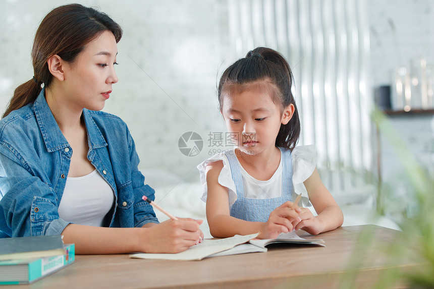 辅导女儿做作业的青年女人图片