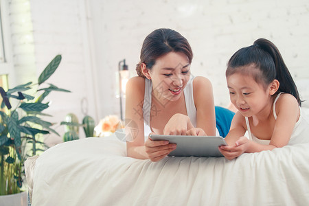 欢迎观临的女孩快乐的母女俩玩平板电脑背景