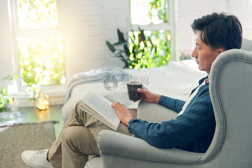 坐在沙发上看书的青年男人图片