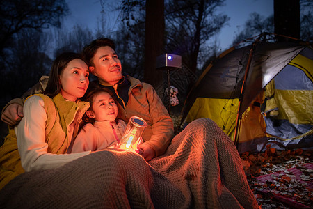 快乐的三口之家夜晚在户外露营图片