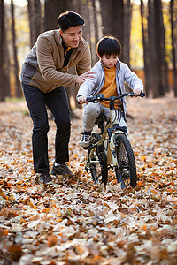 户外学习骑自行车的父子图片